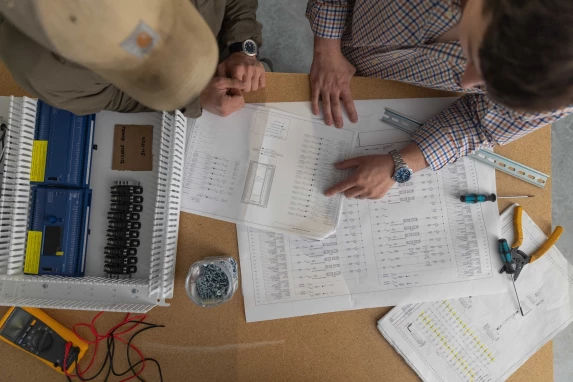 Engineers reviewing electrical drawings and specifications at a worktable